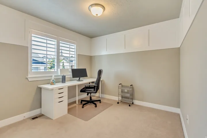 Room featuring a window with white louvered shutters, paneled wainscoting, and a flush-mount ceiling light fixture