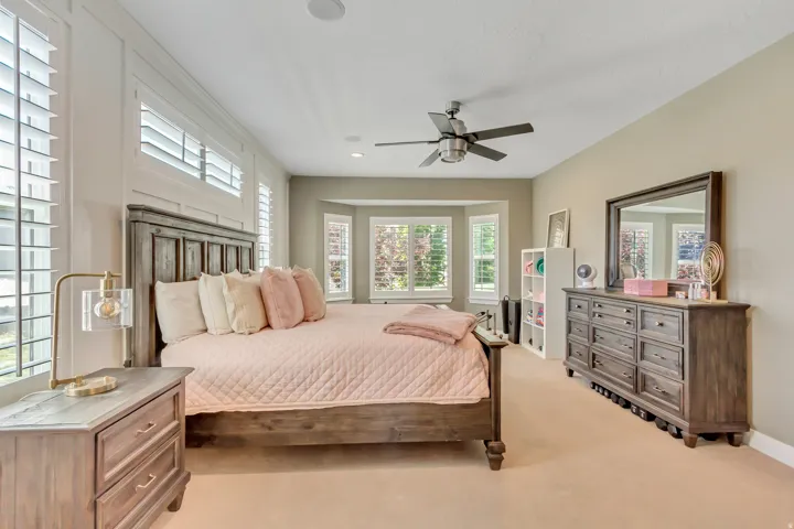 Recessed lighting and a ceiling fan complement the broad windows featuring plantation shutters