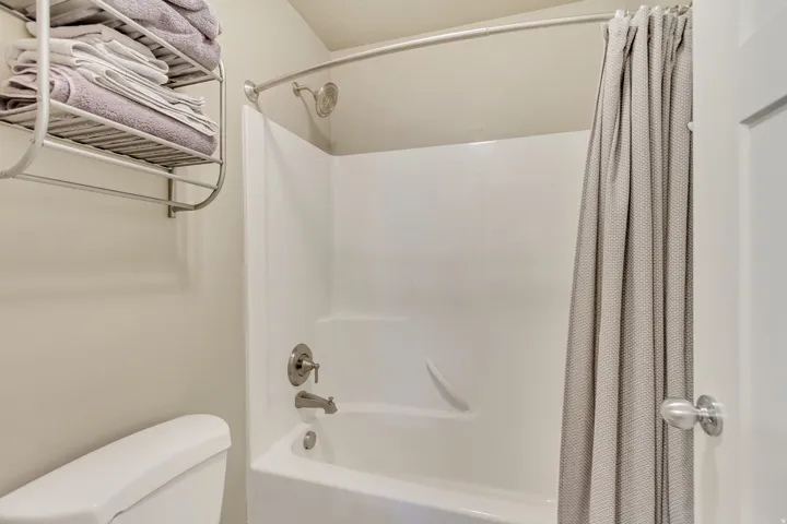 White bathtub and shower combination with brushed nickel fixtures