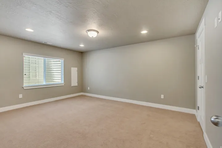 Spacious room featuring neutral carpeting, light neutral wall paint, and white trim