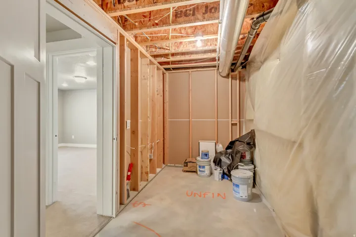 Unfinished basement area with exposed wood framing, concrete flooring, and visible ceiling joists