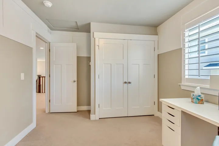 Bedroom featuring neutral-toned walls, white trim, and a built-in closet with double panel doors