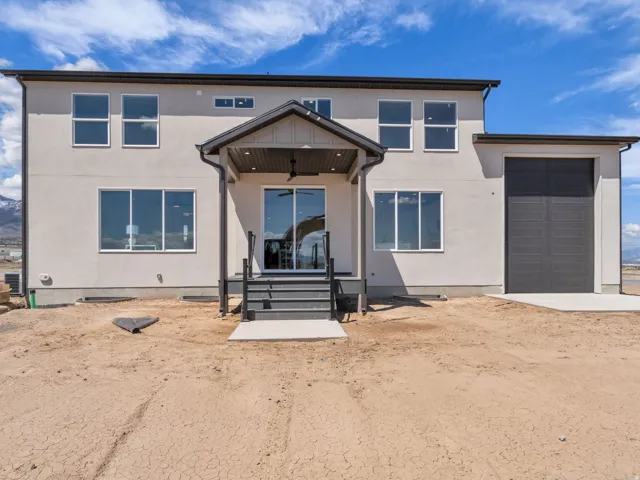Contemporary two-story residence with a stucco exterior, featuring a covered patio with a ceiling fan