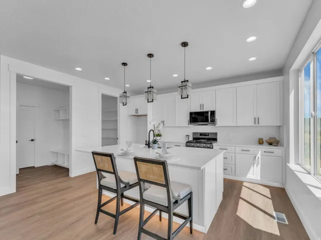 Modern kitchen featuring a large center island, white cabinetry, integrated stainless steel appliances, and wood-finish flooring