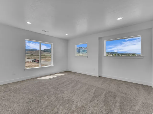 Bright interior space featuring three windows with mountain scenery, recessed ceiling lighting, and neutral-toned carpeting