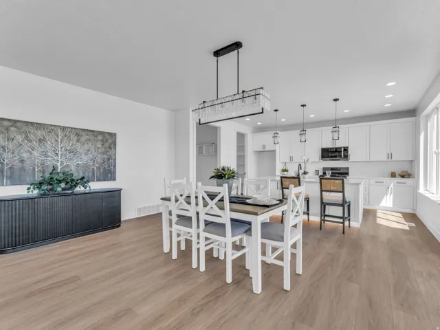 Bright open-concept space featuring wood-finish flooring, a contemporary dining chandelier, and a kitchen with white cabinetry, a center island, and pendant lighting