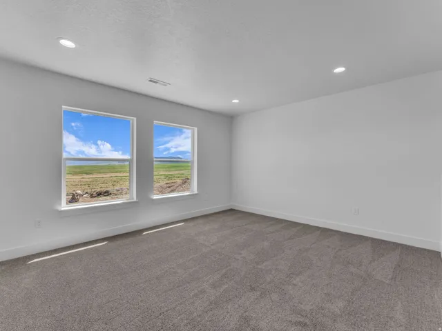 Bright room featuring two windows with white trim, offering expansive views of a lake and surrounding landscape