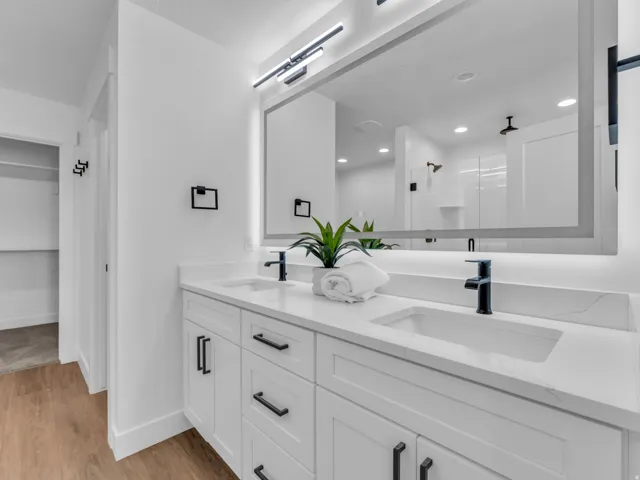 Double vanity featuring white cabinetry with matte black hardware, integrated sinks, and a stone-finish countertop