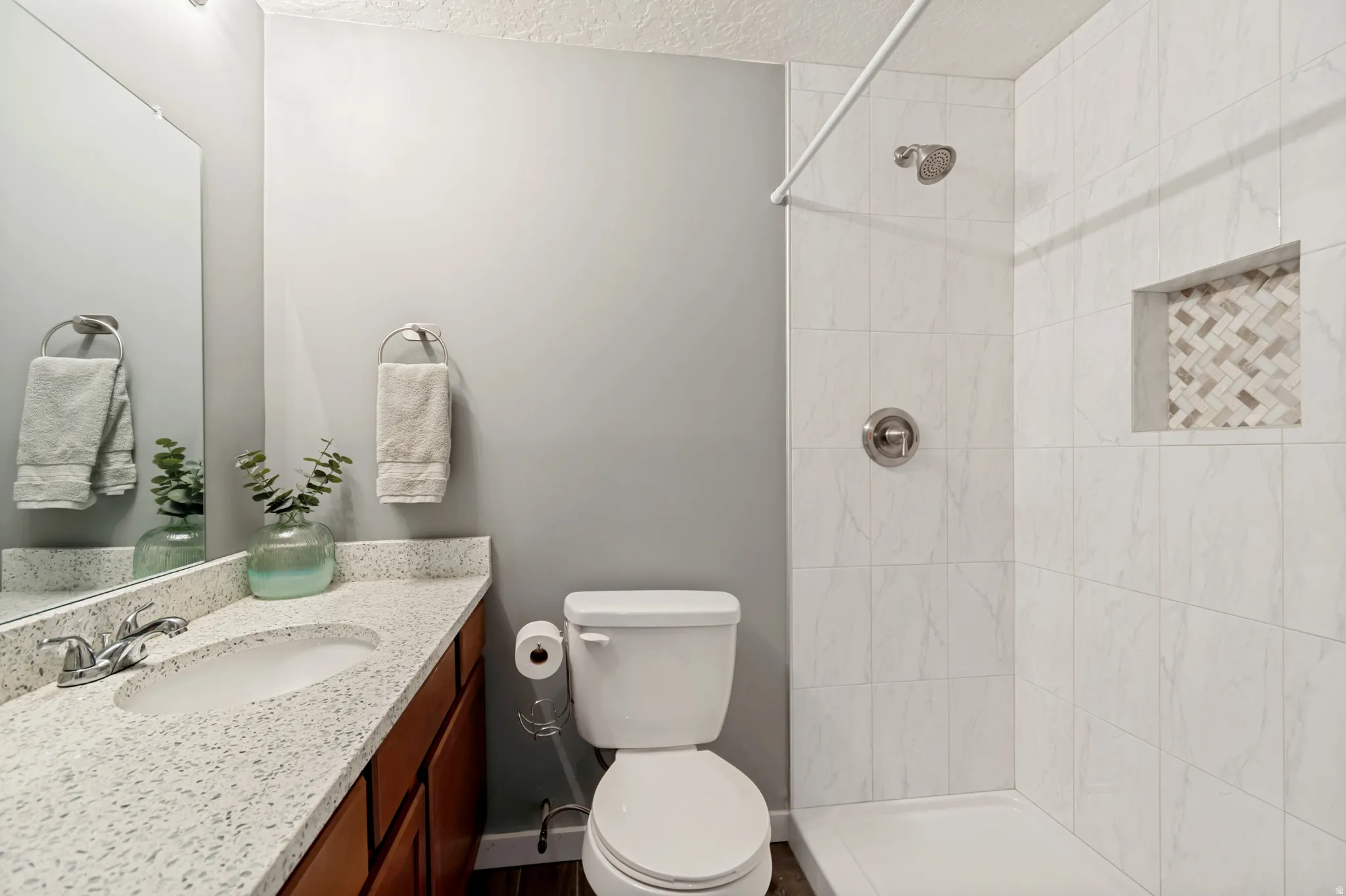Bathroom featuring a wood-finish vanity with a speckled countertop and an integrated sink