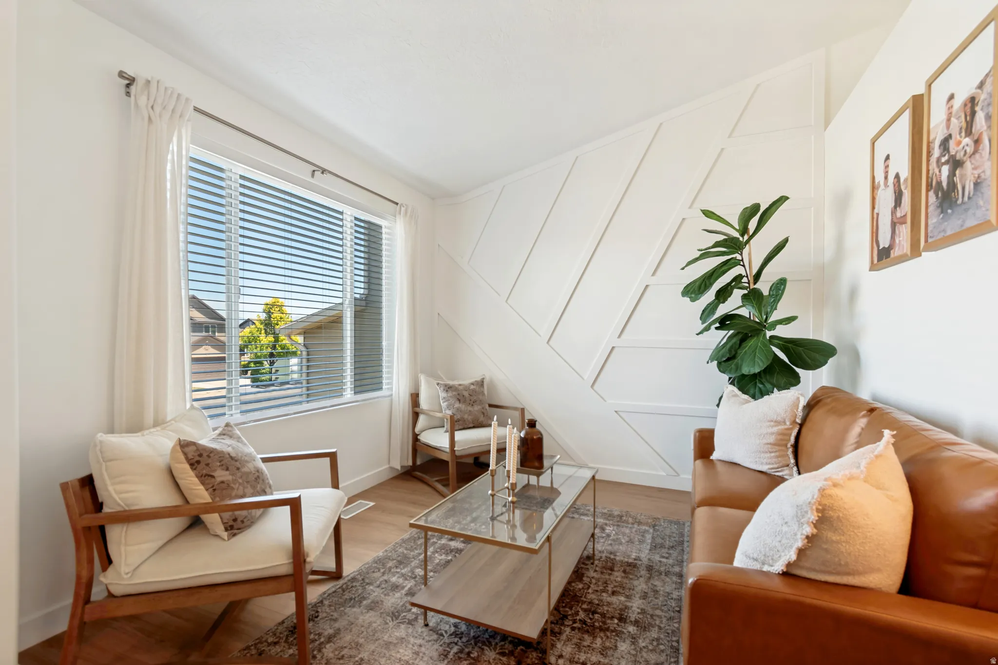Bright living space featuring a large window with blinds, wood-finish flooring, and crown molding