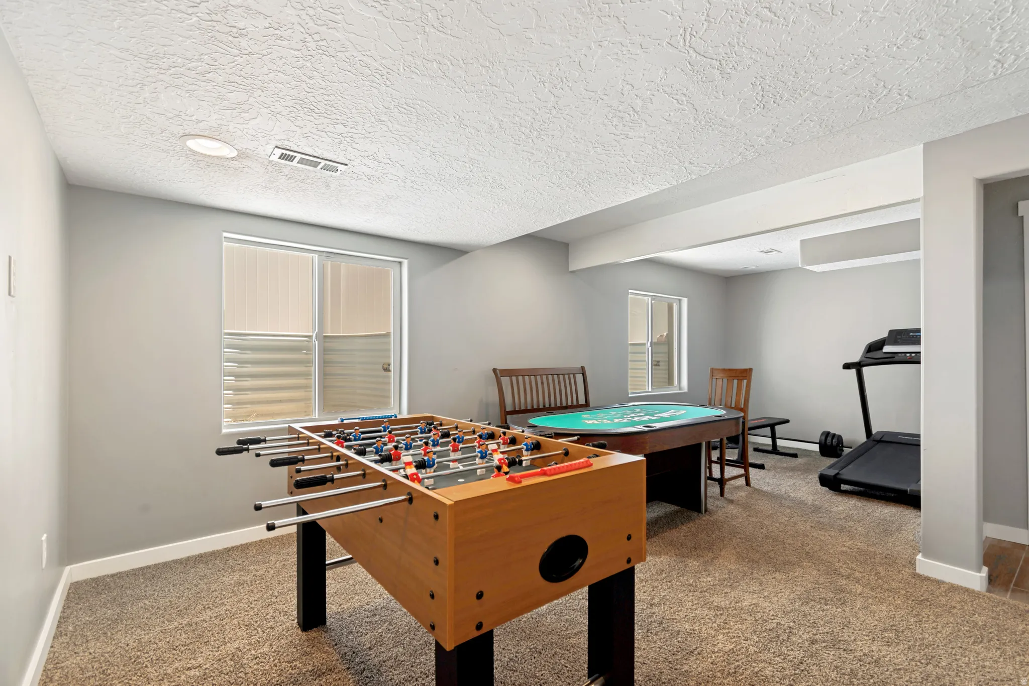 Carpeted recreation space featuring painted walls and a textured ceiling