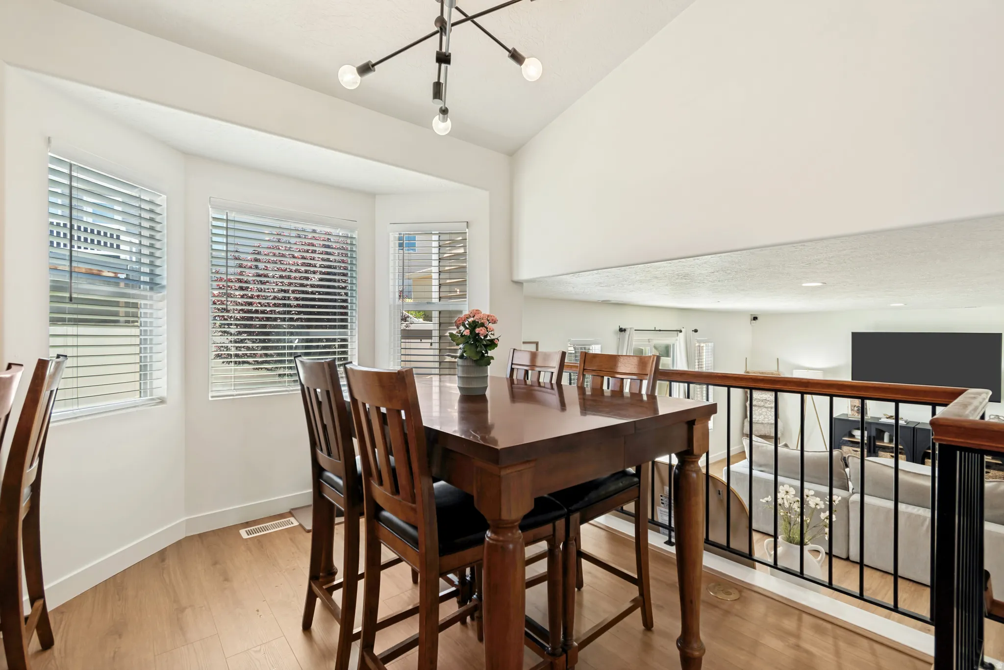 Bright dining area featuring a bay window, wood-finish flooring, and a modern chandelier