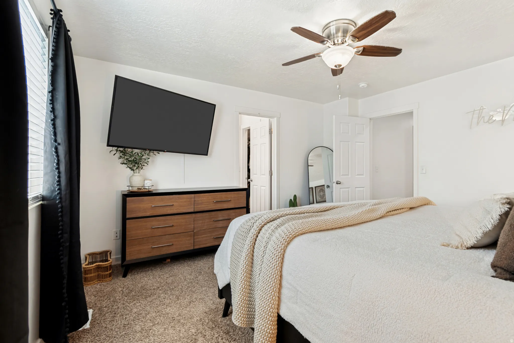 Carpeted room featuring a ceiling fan with light fixture, white walls, and a window with blinds