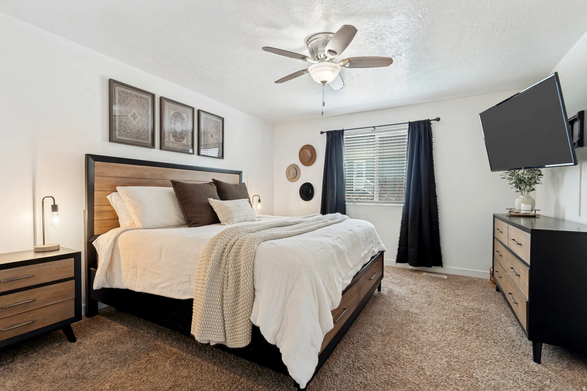Wall-mounted television with a window providing natural light, accompanied by a ceiling fan for climate control