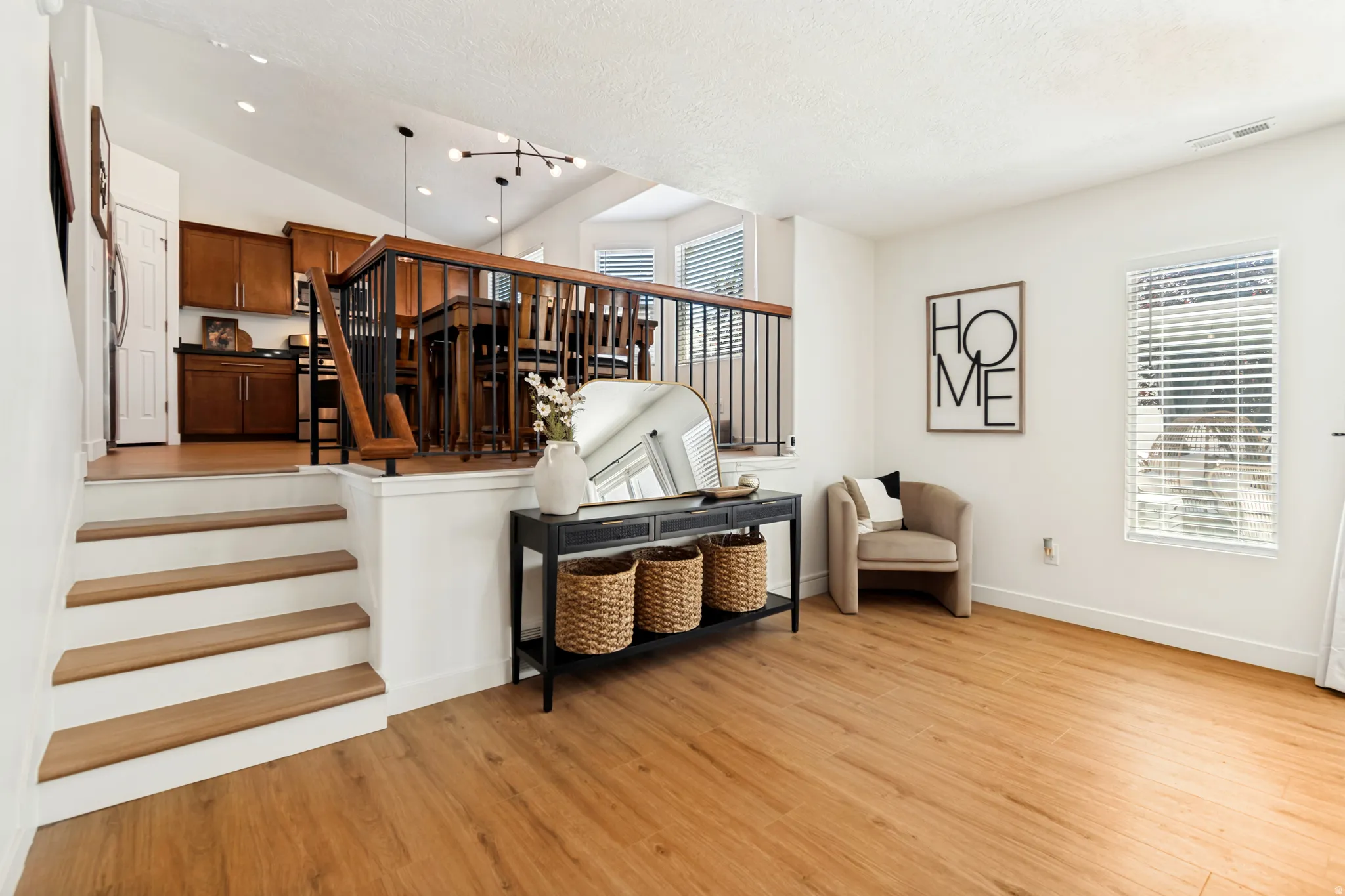 Split-level interior featuring wood-finish flooring, white walls, and bright natural light from a window with blinds