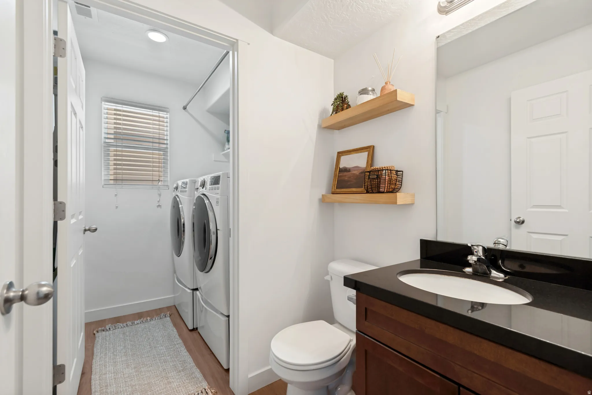 Powder room featuring a dark wood-finish vanity with an integrated sink and dark countertop