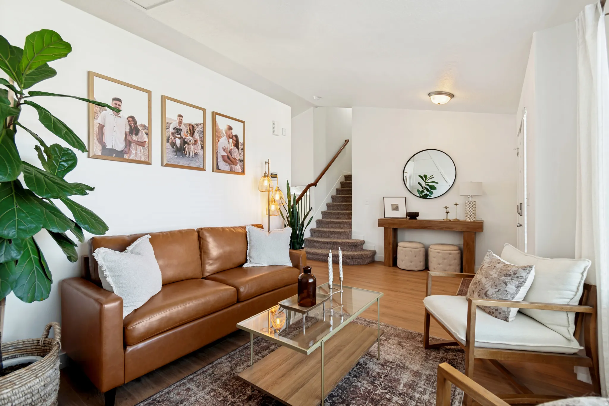Bright living area featuring wood-finish flooring, a staircase with carpeted treads, and white walls