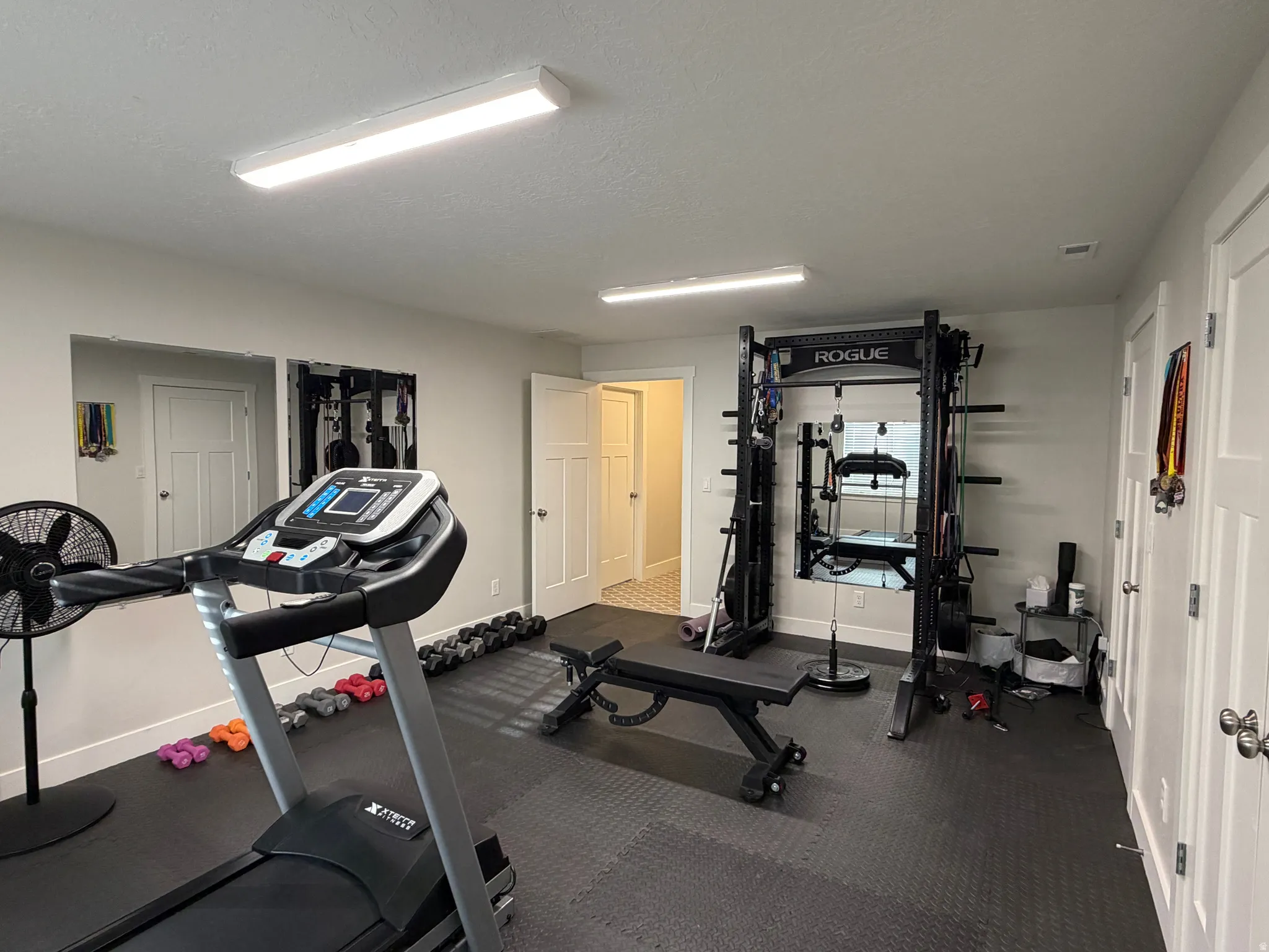 Dedicated fitness space featuring rubber flooring, recessed lighting, and white paneled doors