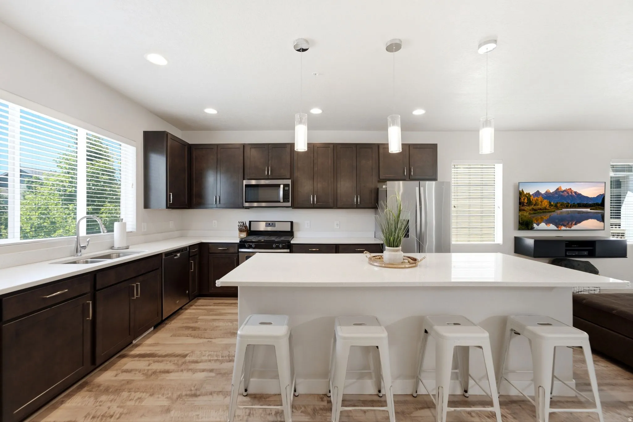 Modern kitchen featuring dark wood cabinetry, light-toned wood-finish flooring, and white countertops