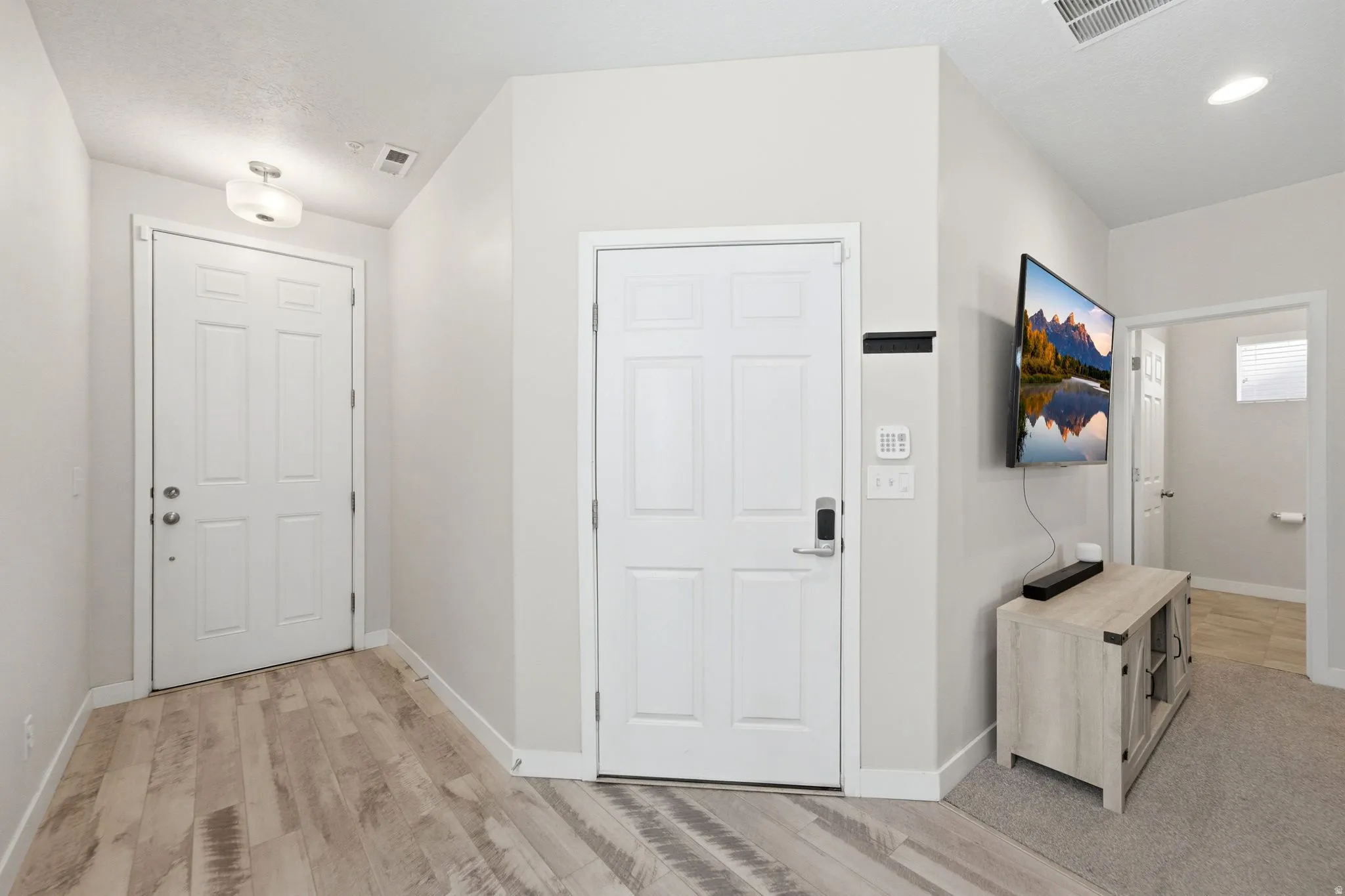 Light-toned wood-finish flooring extends through the entry, complemented by white interior doors and trim