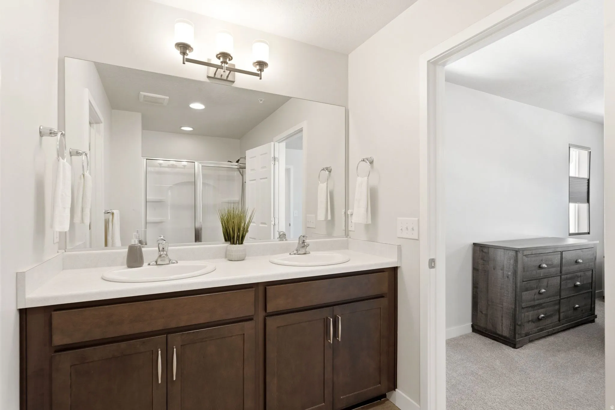 Double vanity featuring white countertops, undermount sinks, and dark wood-finish cabinetry
