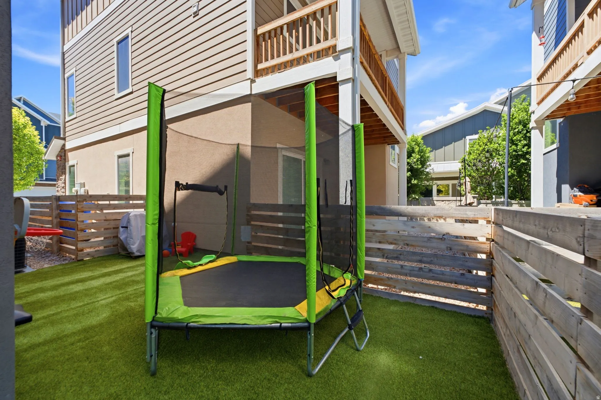 Private outdoor space featuring artificial turf, wooden privacy fencing, and an elevated wooden deck