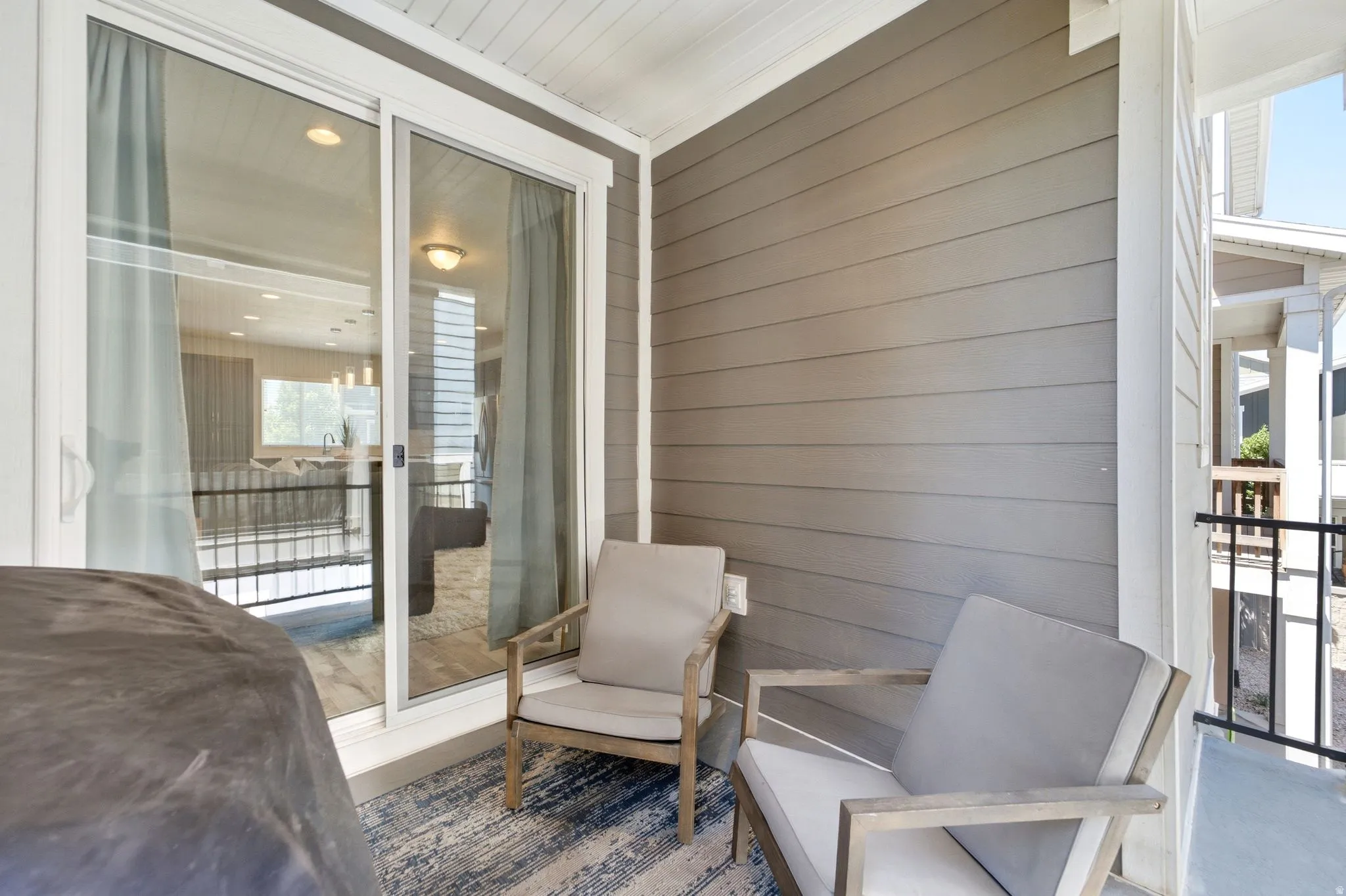 Covered outdoor patio featuring light gray siding and a sliding glass door