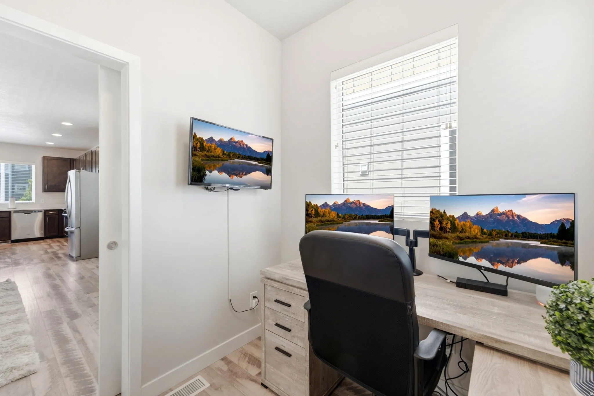 Dedicated office space featuring wood-finish flooring and a window with blinds