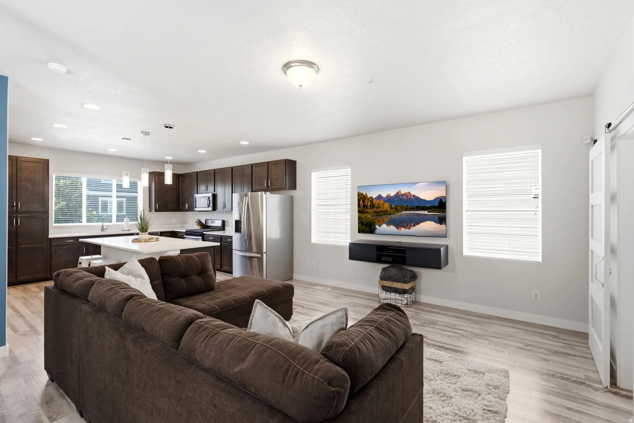 Open-concept living space featuring wood-finish flooring, recessed lighting, and ample natural light from multiple windows