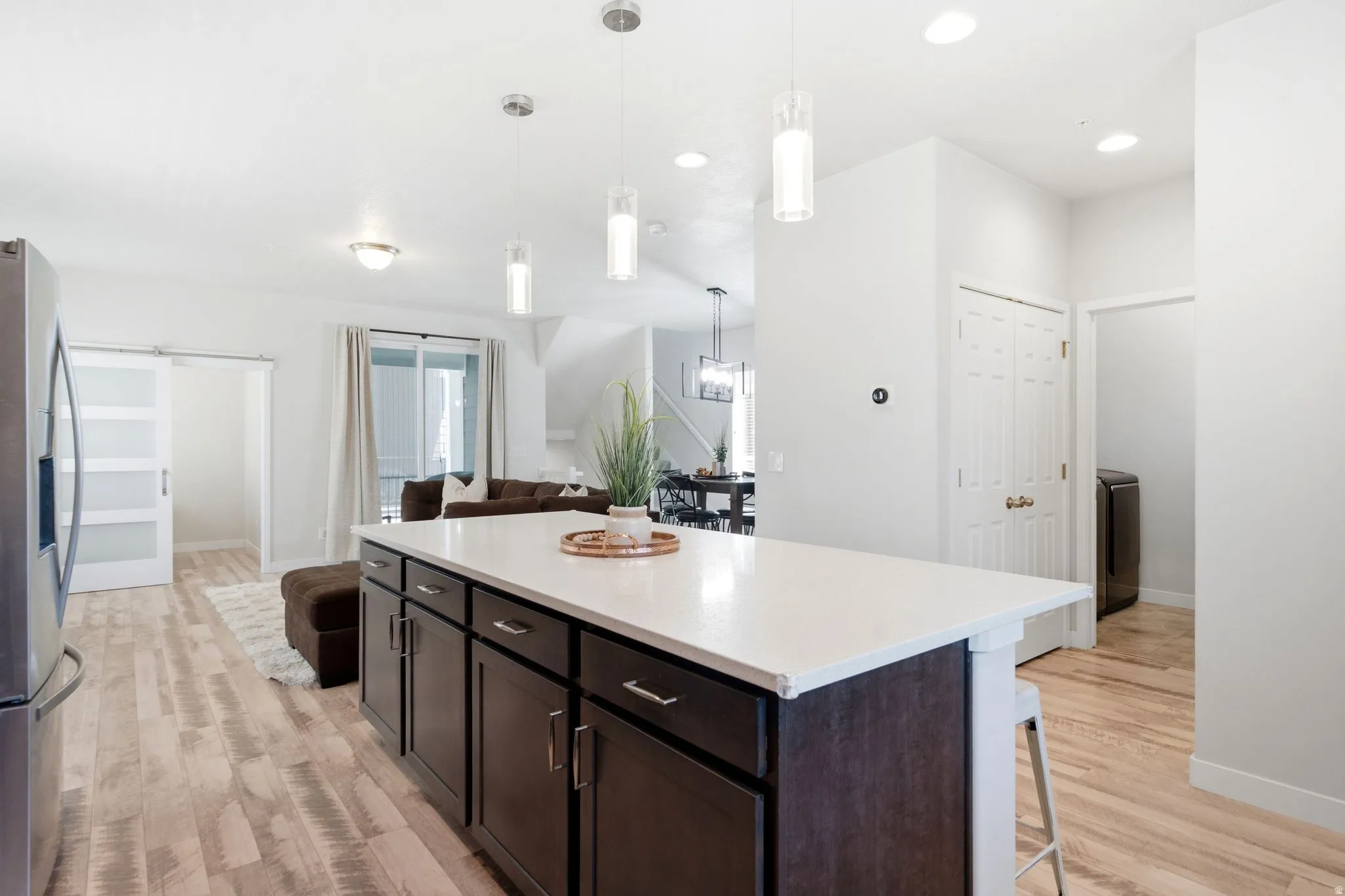 Kitchen island with white countertop and dark cabinetry, complemented by wood-finish flooring