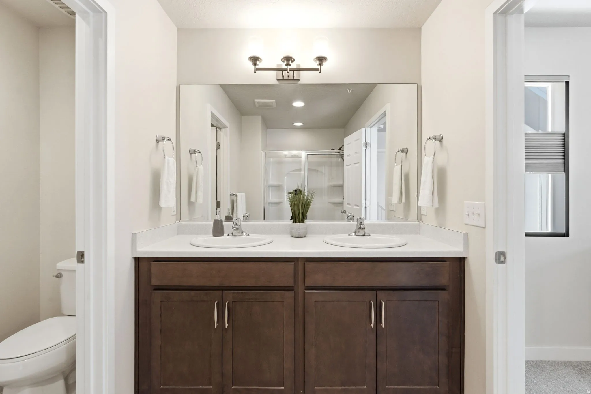 Bathroom featuring a dual vanity with dark wood-finish cabinetry, white countertop, and two undermount sinks