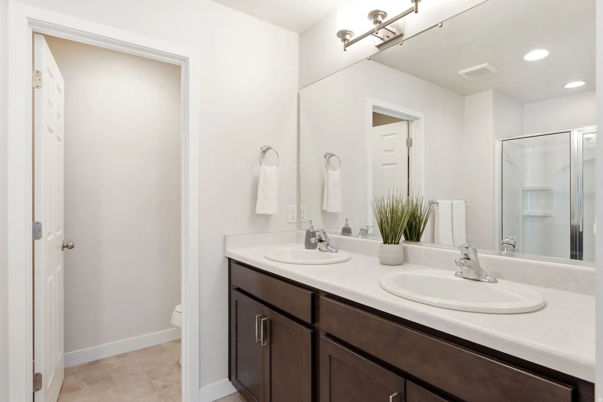Bathroom vanity featuring dual undermount sinks, a light-colored countertop, and dark wood-finish cabinetry