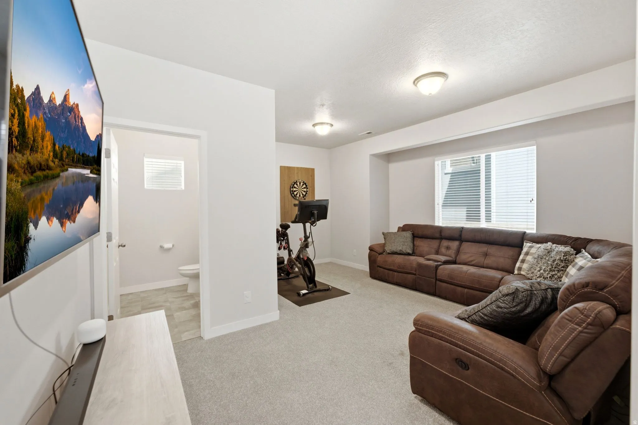 Spacious room featuring light-colored carpeting, recessed lighting, and a window with horizontal blinds