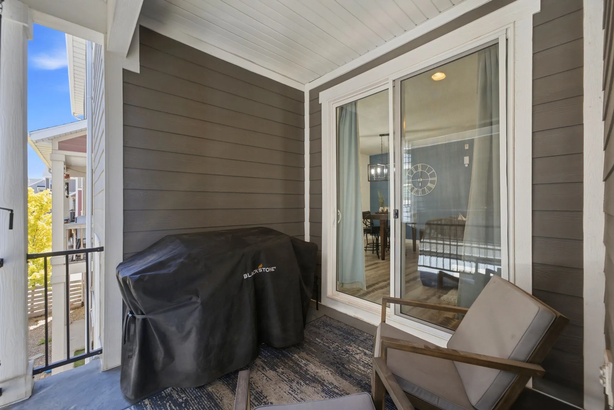 Covered patio featuring plank siding, white trim, and a sliding glass door