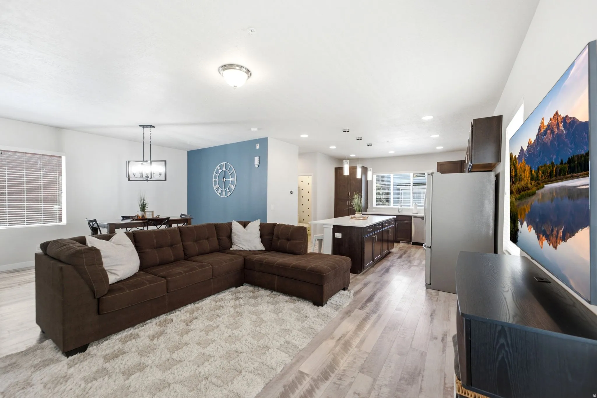 Open-concept living space featuring wood-finish flooring, recessed lighting, and a kitchen with an island and stainless steel appliances