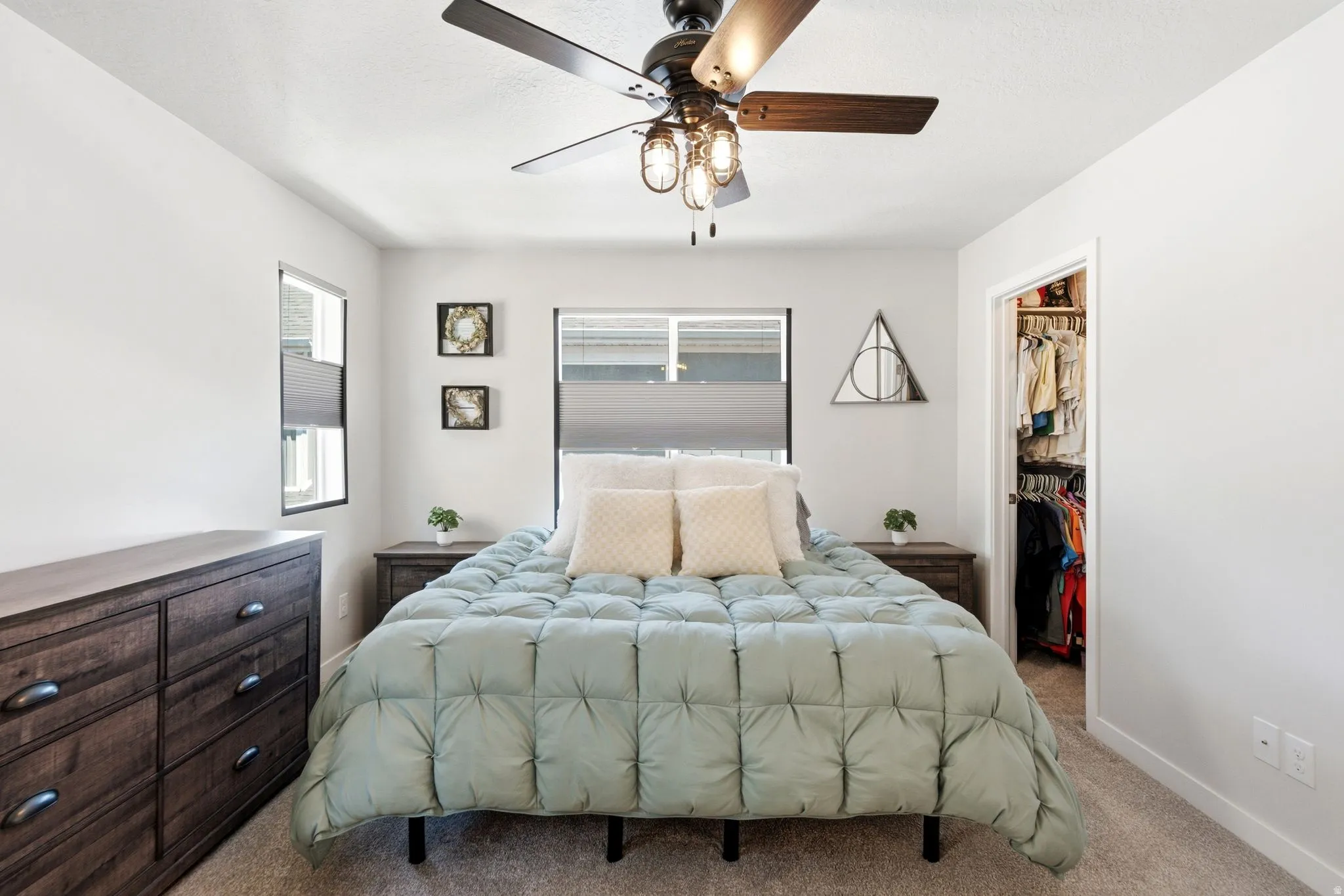 Bedroom featuring light gray wall paint, textured carpet flooring, and a ceiling fan with integrated lighting