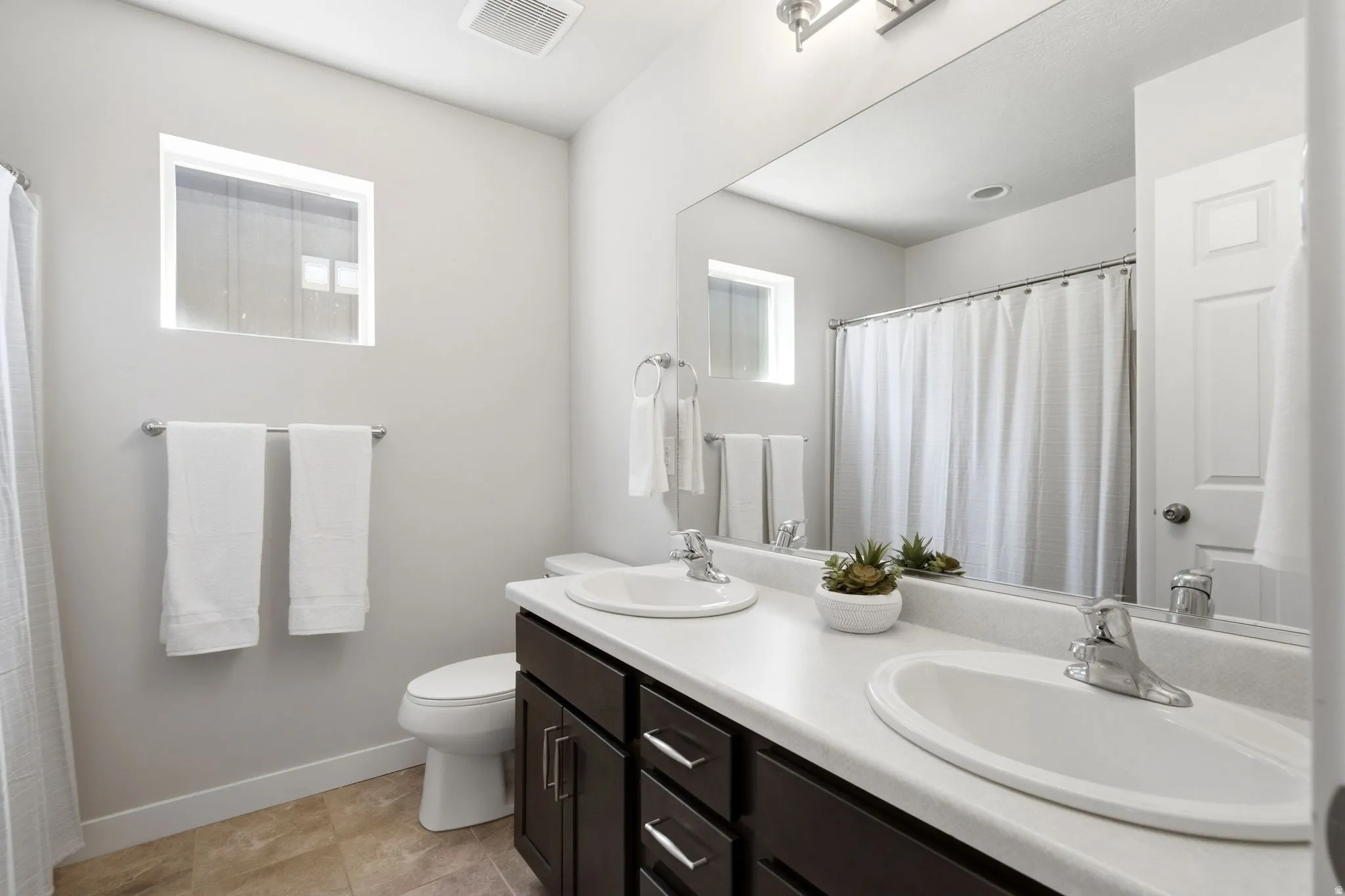 Dual sink vanity with dark wood-finish cabinetry and chrome fixtures