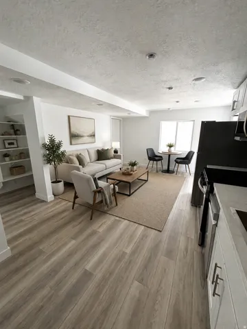 Open-concept living space featuring wood-finish flooring, recessed lighting, built-in shelving, and white cabinetry with dark hardware