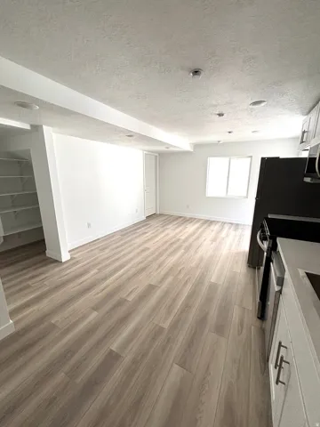 Open-concept living area featuring wood-finish flooring, recessed lighting, a window, and white walls