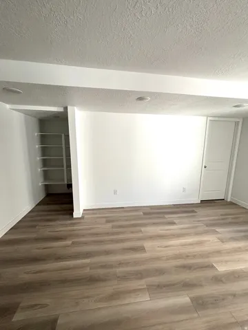Spacious room featuring wood-finish flooring, white baseboards, and recessed lighting