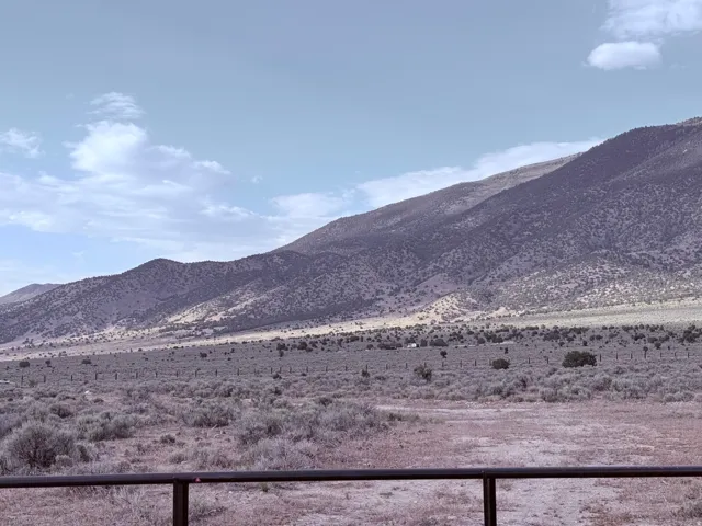 Expansive mountain landscape featuring natural desert vegetation, distant mountains, and open terrain under a clear sky