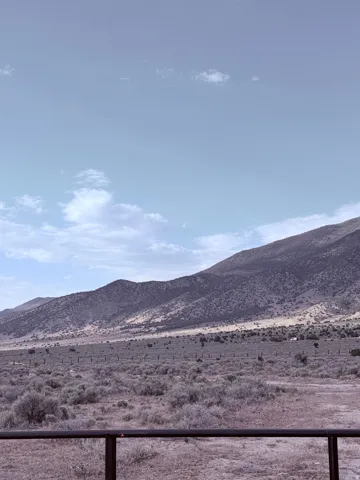 Expansive mountain landscape with diverse terrain, featuring undulating hills, natural vegetation, and a clear sky