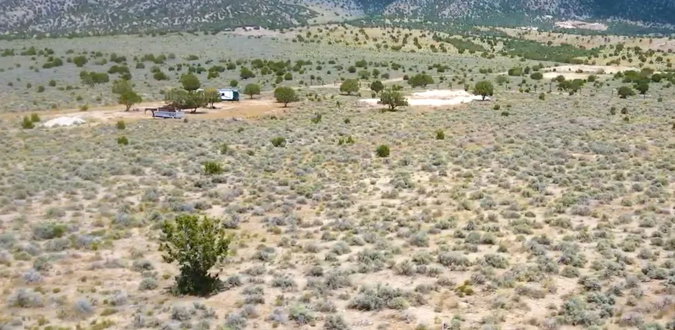 Expansive desert landscape featuring natural scrub brush and distant mountain terrain