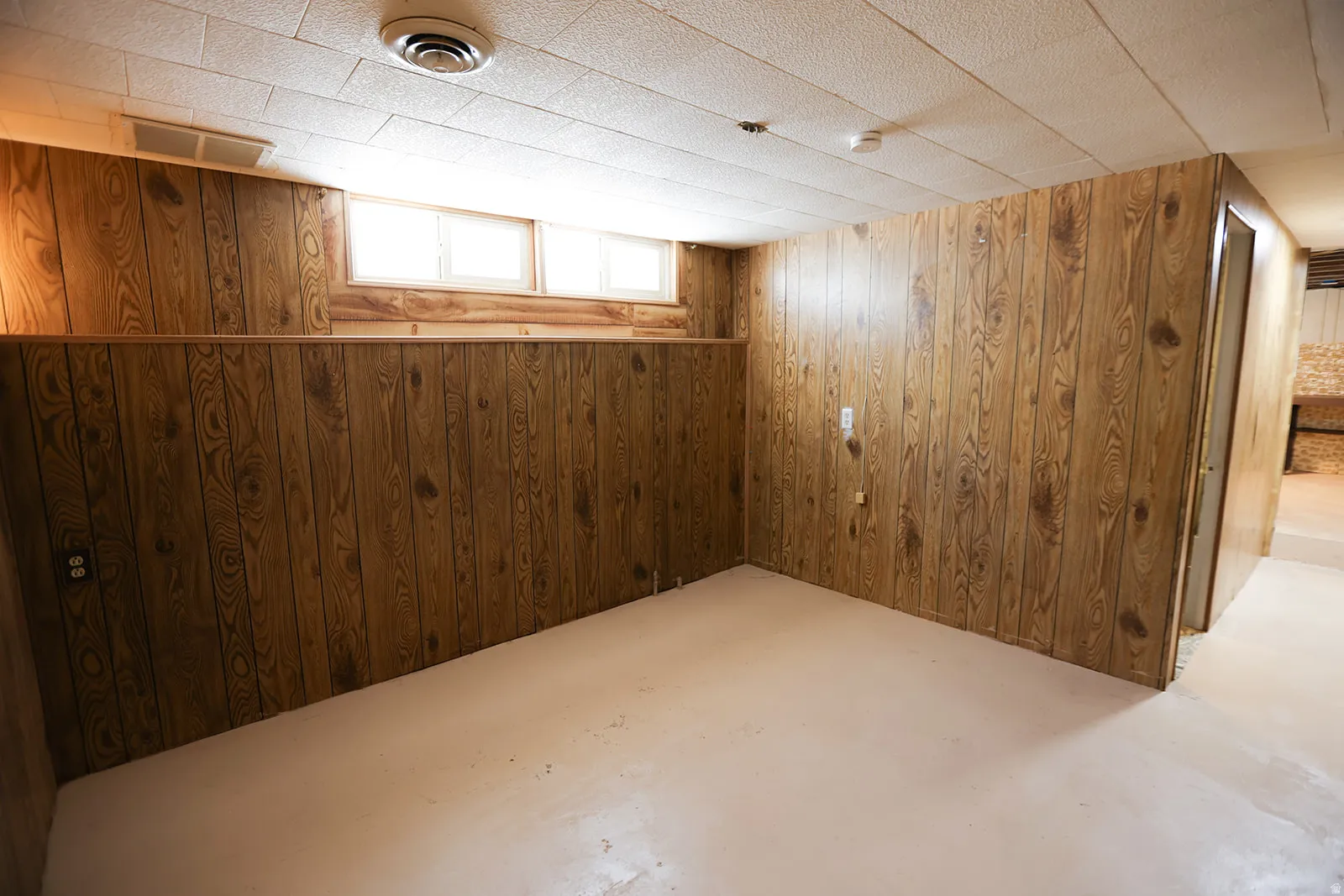Interior space featuring wood paneling, a drop ceiling, and a concrete floor