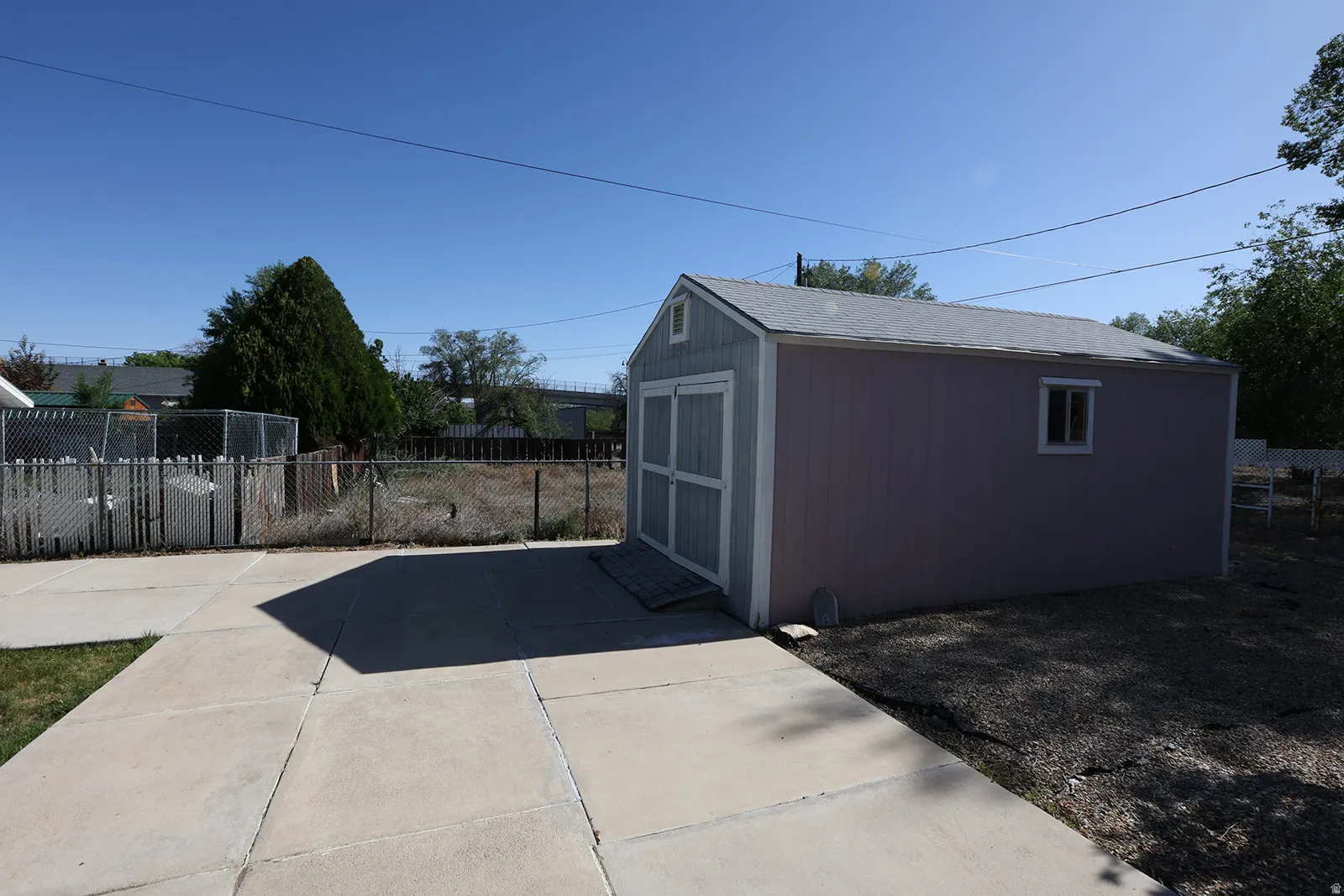 Detached outdoor storage shed with a gabled roof, a single window, and a light-colored exterior