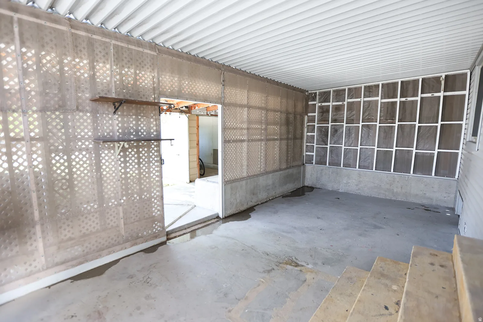 Covered outdoor patio area featuring a concrete floor, slatted ceiling, and lattice wall panels