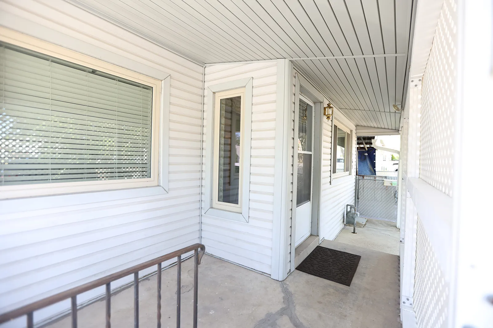 Covered porch entry featuring white vinyl siding