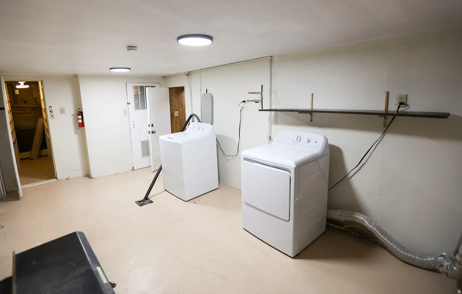Laundry area, painted concreate floor, white walls, and flush-mount ceiling lighting