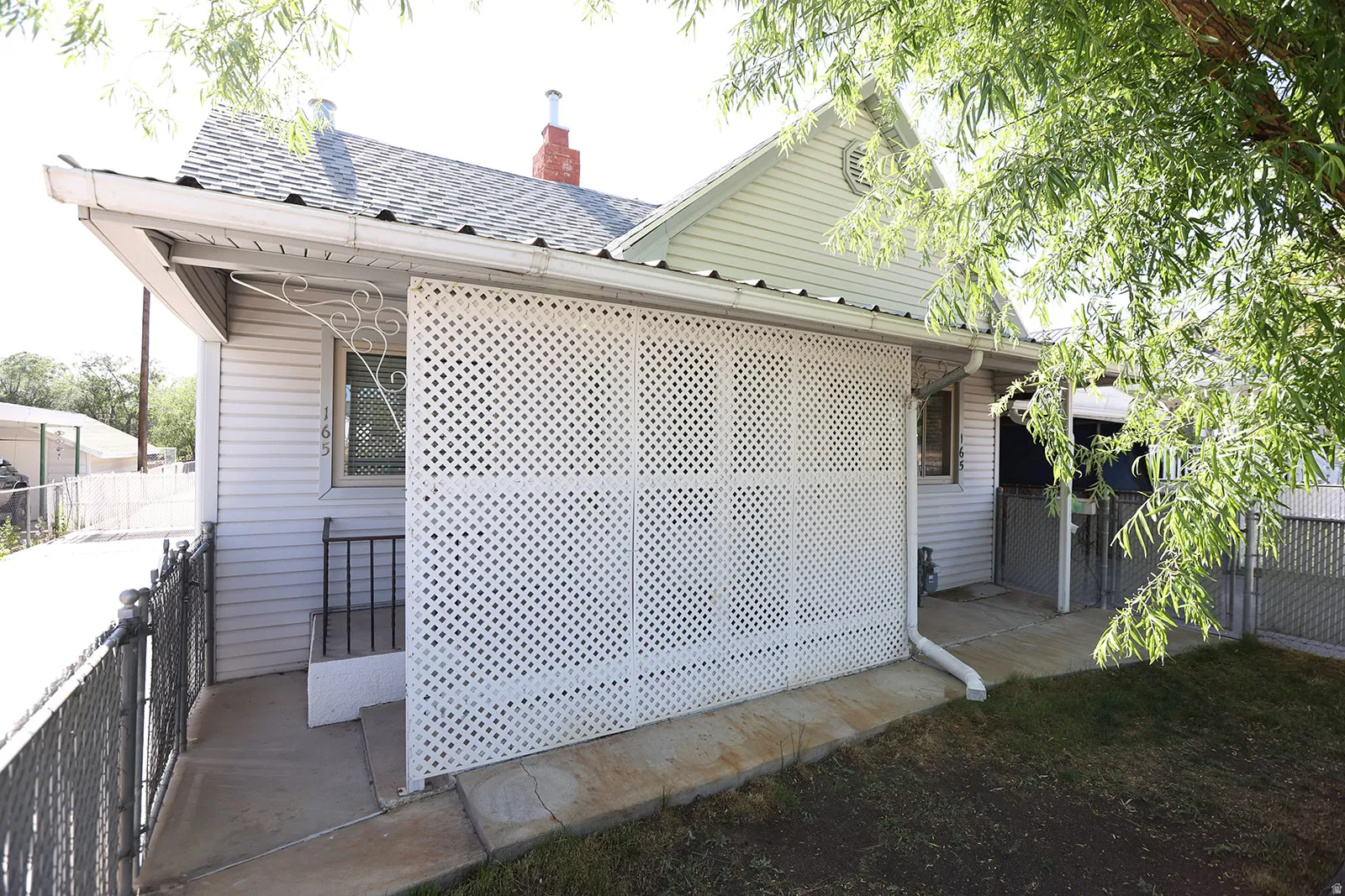 Exterior with white siding, covered entry, and decorative lattice paneling