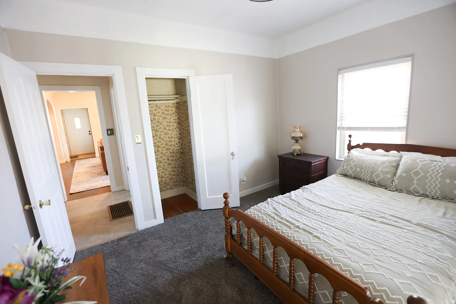 Carpeted bedroom featuring window with blinds, sliding glass doors leading to the backyard, closet, and doorway leading to a hallway